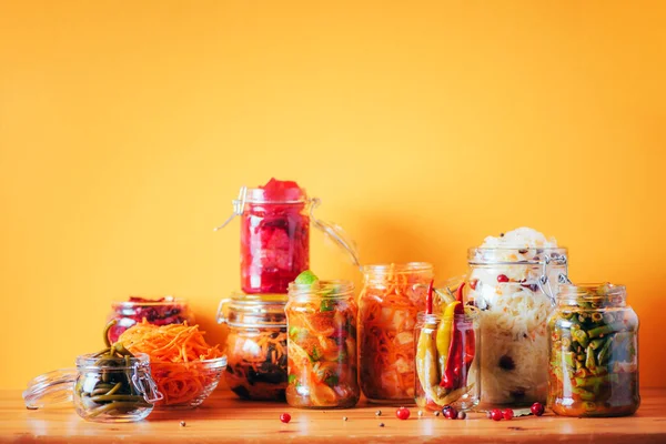 Surtido de diversos alimentos fermentados y marinado sobre fondo de madera, espacio de copia. Verduras fermentadas, chucrut, pimienta, ajo, remolacha, zanahoria coreana, kimchi de pepino en frascos de vidrio. — Foto de Stock