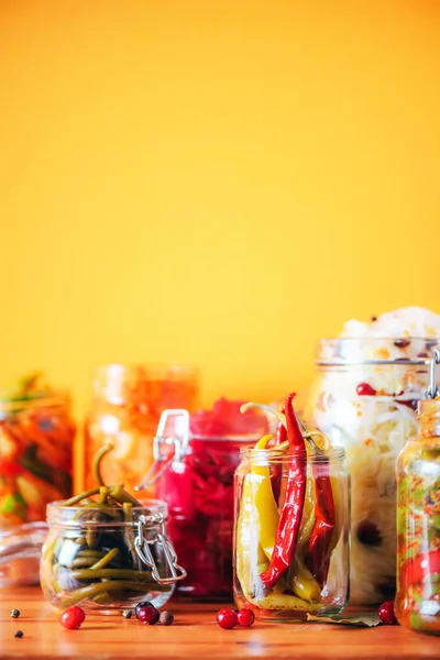 Assortment of various fermented and marinated food over wooden background, copy space. Fermented vegetables, sauerkraut, pepper, garlic, beetroot, korean carrot, cucumber kimchi in glass jars. — Stock Photo, Image