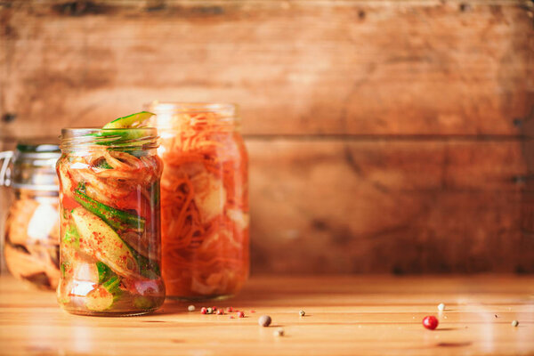 Assortment of various fermented and marinated food over wooden background, copy space. Fermented vegetables, sauerkraut, pepper, garlic, beetroot, korean carrot, cucumber kimchi in glass jars.