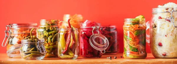 Assortment of various fermented and marinated food over wooden background, copy space. Fermented vegetables, sauerkraut, pepper, garlic, beetroot, korean carrot, cucumber kimchi in glass jars. — Stock Photo, Image