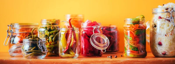 Surtido de diversos alimentos fermentados y marinado sobre fondo de madera, espacio de copia. Verduras fermentadas, chucrut, pimienta, ajo, remolacha, zanahoria coreana, kimchi de pepino en frascos de vidrio. — Foto de Stock