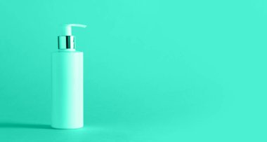 Nane rengi arka planda fotokopi alanı olan beyaz bir nemlendirici losyon şişesi. Minimalizm tarzı. Moda yeşili ve turkuaz rengi. Cilt bakımı, vücut bakımı, güzellik konsepti