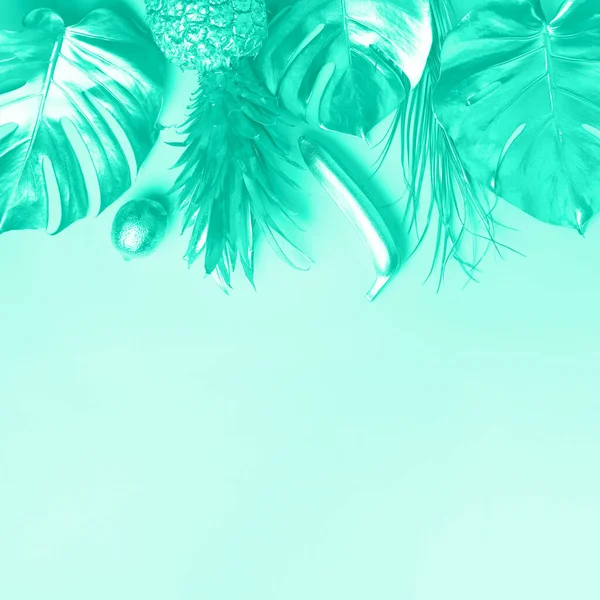 Diseño creativo. Piña dorada y palmera, monstera sobre fondo de color menta con espacio para copiar. Vista superior. Asiento plano tropical. Concepto de comida exótica. Color verde y turquesa de moda . — Foto de Stock