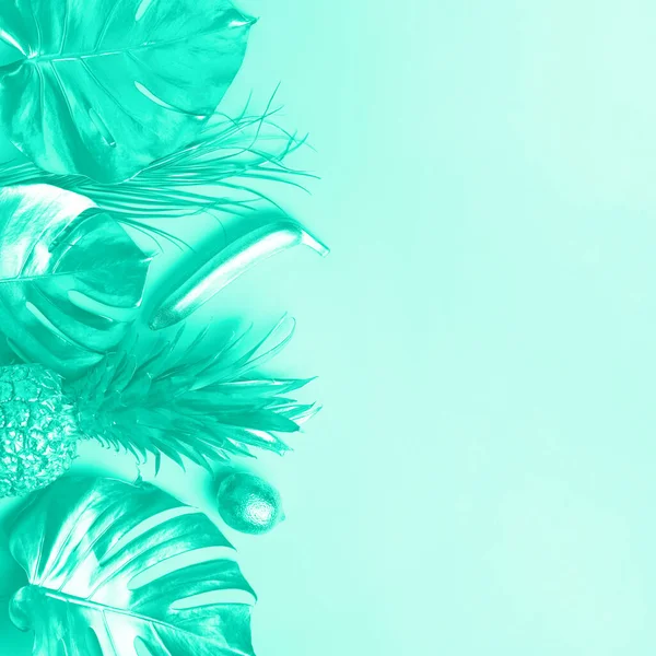 Diseño creativo. Piña dorada y palmera, monstera sobre fondo de color menta con espacio para copiar. Vista superior. Asiento plano tropical. Concepto de comida exótica. Color verde y turquesa de moda . —  Fotos de Stock