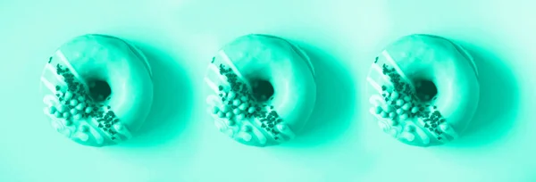 Rosa Donut-Muster mit Sahnehäubchen auf mintfarbenem Hintergrund. Leckerer Donut. Trendy grün und türkis. Kopierraum, Ansicht von oben — Stockfoto