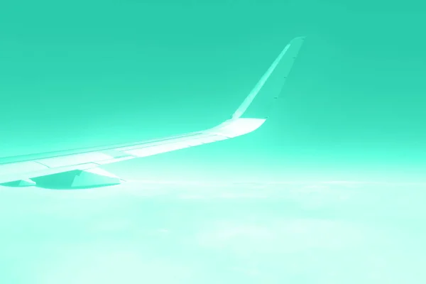 Travel concept. Wing of airplane flying above the clouds in trendy color sky. Mint green and turquoise color. Copy space — Stock Photo, Image