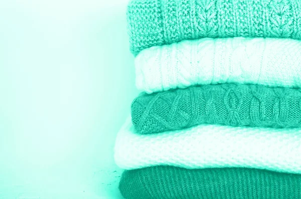 Pile of knitted wool sweaters in mint color background with copy space. Knitwear, clothes. Trendy green and turquoise color. — Stock Photo, Image