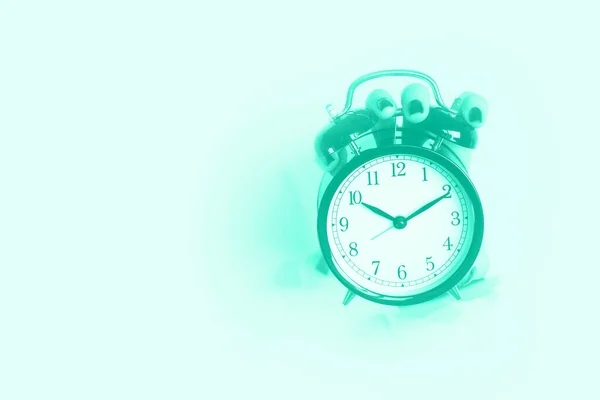 Hand houden van zwarte wekker door gat in mint kleur achtergrond. Wakker worden alert concept. Trendy groene en turquoise kleur. Goedemorgen routine. Banner met kopieerruimte — Stockfoto