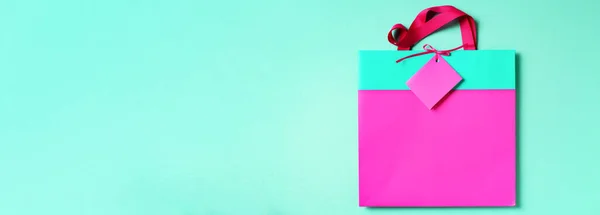 Banner de turquesa y bolsa de compras de papel rosa sobre fondo verde de moda. Copiar espacio. Concepto de regalo. Día de las mujeres. Día de San Valentín. Listo para fiesta de cumpleaños. — Foto de Stock