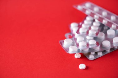 Kırmızı arka planda bir sürü beyaz kapsül var. Uzayı kopyala Bir sürü ilaç, soğuk algınlığı tedavisi. Coronavirus Covid-19.