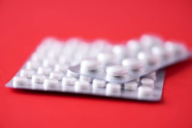 Kırmızı arka planda bir sürü beyaz kapsül var. Uzayı kopyala Bir sürü ilaç, soğuk algınlığı tedavisi. Coronavirus Covid-19.