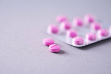 Pembe kapsül, haplar, gri arka planda vitaminler. Uzayı kopyala Bir sürü ilaç, soğuk algınlığı tedavisi. Kadın hastalıkları tedavisi. Pankart