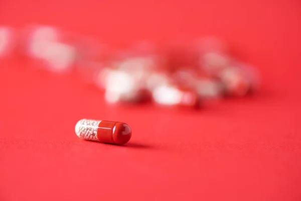 Червоні капсули на червоному тлі. Копіюю простір. Группа наркотиков, холодное лечение гриппом. Коронавірус Ковід-19. — стокове фото