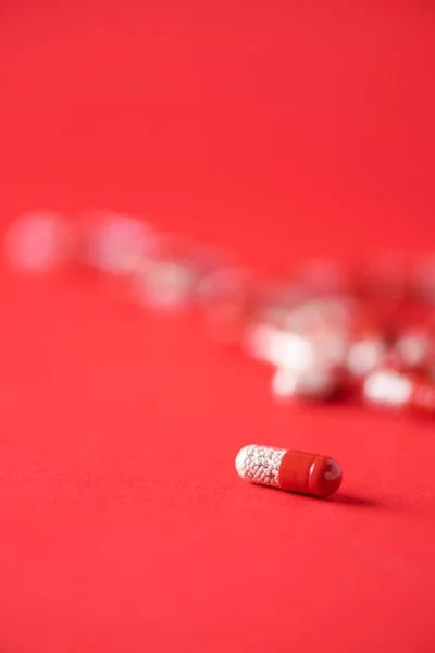 Macro of red capsules on red background. Copy space. Bunch of drugs, cold flu treatment. Coronavirus Covid-19. — Stock Photo, Image