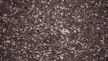 Rotasyon arka planında Chia tohumları. Sağlıklı yemek, süper tohum dokusu. Yemek malzemesi geçmişi. Üst düzey, sağlıklı yaşam tarzı konsepti. Vejetaryen sağlıklı beslenme. Yemek pişirme süreci.