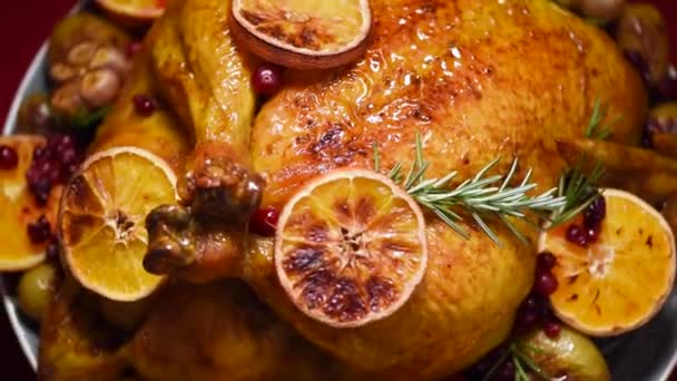 Weihnachtsessen für die Familie. Gebratenes Huhn mit Kräutern, Orangen, Preiselbeeren auf rotierendem Hintergrund, Shooting in Zeitlupe. — Stockvideo