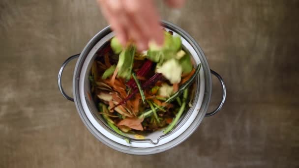 Reduce el desperdicio. Las mujeres arrojan cáscaras de verduras, desechos y cáscaras de frutas en el cubo de compost. Vista superior. Clasificación de residuos domésticos, compostaje, reciclado, cero residuos — Vídeo de stock