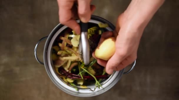 Riduzione degli sprechi alimentari. Le donne gettano peeling vegetale, scarti e bucce di frutta nel secchio del compost. Vista dall'alto. Selezione dei rifiuti domestici, compostaggio, riciclaggio, zero rifiuti — Video Stock