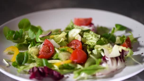 野菜サラダの準備,キュウリ,トマト,コショウ.石皿の上に緑のサラダが落ちる。最上階だ。ビーガン・ローフードのコンセプト. — ストック動画