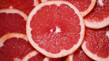 Dönen arka planda greyfurt dilimlenmiş. Turunçgil meyvesi. Vegan ve çiğ gıda konsepti. Kırmızı greyfurt dokusu. Üst görünüm