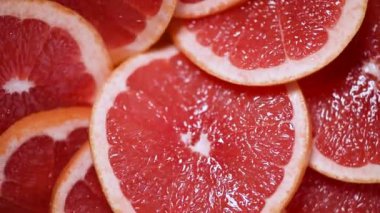 Dönen arka planda greyfurt dilimlenmiş. Turunçgil meyvesi. Vegan ve çiğ gıda konsepti. Kırmızı greyfurt dokusu. Üst görünüm