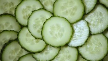 Dilimlenmiş salatalık dönüşünün en üst görüntüsü. Vegan ve çiğ gıda konsepti. Sulu salatalık dokusu