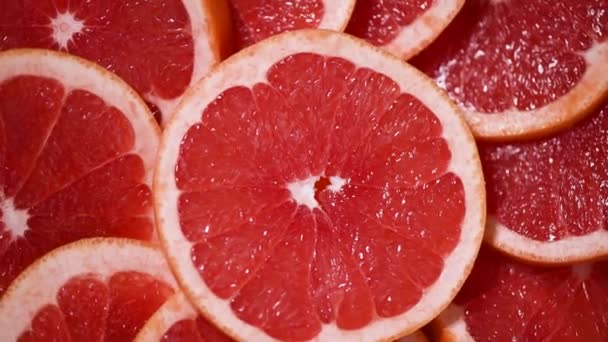Grapefruit krájel polovinu na rotujícím pozadí. Citrusové plody. Veganská a syrová strava. Červené grapefruity. Horní pohled — Stock video