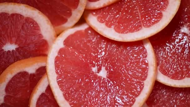 Grapefruit zur Hälfte auf rotierendem Hintergrund geschnitten. Zitrusfrüchte. Veganes und Rohkost-Konzept. Rote Grapefruits. Ansicht von oben — Stockvideo