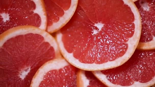Grapefrukt skivad hälften på roterande bakgrund. Citrusfrukter. Vegansk och raw food koncept. Röd grapefruktstruktur. Ovanifrån — Stockvideo