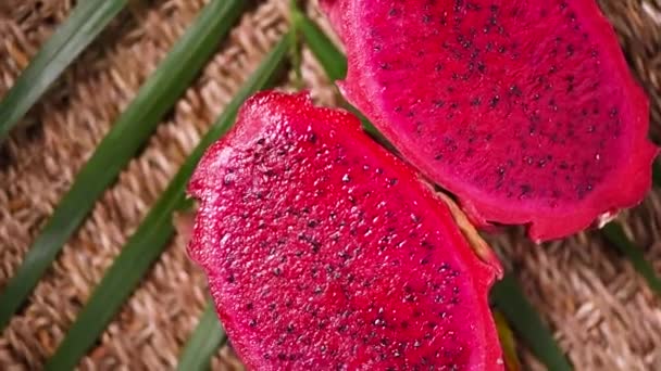 Fruta de dragão suculenta no ramo de palma, fundo rotativo. Vista superior. Frutas cítricas. Vegan e conceito de alimentos crus. Textura de pitahaya em fatias — Vídeo de Stock