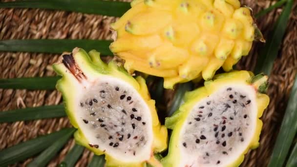 Жовта піжама на пальмовій гілці, обертається на фоні. Вид зверху. Цитрусові фрукти. Концепція веганської та сирої їжі. Фруктова текстура нарізаного дракона — стокове відео