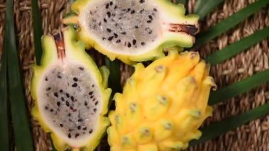 Palmiye dalında sarı pitahaya, döner arka plan. Üst Manzara. Turunçgil meyvesi. Vegan ve çiğ gıda konsepti. Dilimlenmiş ejderha meyve dokusu