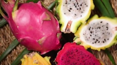 Palmiye dalında sarı ve pembe pitahaya, döner arka plan. Üst Manzara. Turunçgil meyvesi. Vegan ve çiğ gıda konsepti. Dilimlenmiş ejderha meyve dokusu