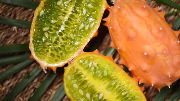 Afrikaanse gehoornde meloen met draaiende achtergrond. Bovenaanzicht. Exotische Kiwano meloen vruchten, tropische palmtak. Veganistisch en rauw voedselconcept. — Stockvideo