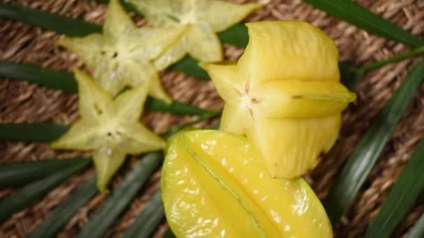 Gelbe Karambolafrucht auf rotierendem Hintergrund. Ansicht von oben. Exotische Früchte, tropischer Palmenzweig. Veganes und Rohkost-Konzept. — Stockvideo