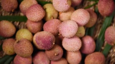 Dönen arka planda taze liçi meyveleri. Üst Manzara. Egzotik meyveler, tropik palmiye dalları. Vegan ve çiğ gıda konsepti.