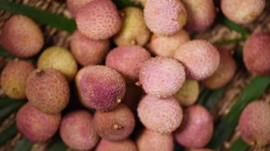 Dönen arka planda taze liçi meyveleri. Üst Manzara. Egzotik meyveler, tropik palmiye dalları. Vegan ve çiğ gıda konsepti.