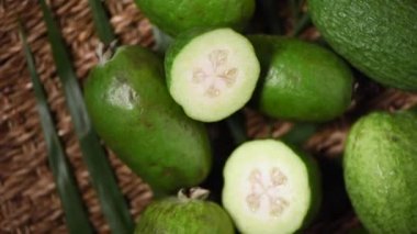 Dönen arka planda yeşil feijoa meyveleri. Üst Manzara. Egzotik meyve, tropik palmiye dalı. Vegan ve çiğ gıda konsepti.