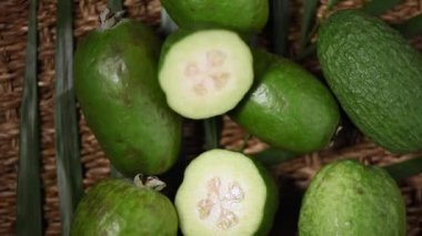 Dönen arka planda yeşil feijoa meyveleri. Üst Manzara. Egzotik meyve, tropik palmiye dalı. Vegan ve çiğ gıda konsepti.