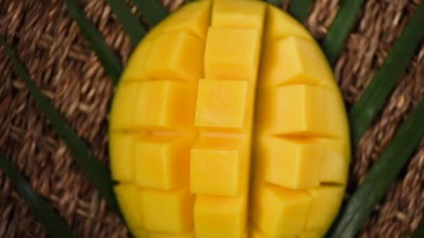 Felvágott mangó forgó háttérrel. Első látásra. Egzotikus gyümölcs, trópusi pálmaág. Vegán és nyers élelmiszer fogalma — Stock videók