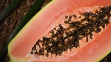 Dönen arka planda olgun papaya. Üst Manzara. Egzotik meyve, tropik palmiye dalı. Vegan ve çiğ gıda konsepti. Kesilmiş papaya.