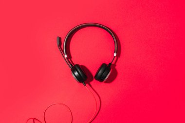 Müzik ve ses konsepti. Kırmızı arka planda siyah kulaklıklar. Üst Manzara. Uzayı kopyala Şehir yaz zamanı. Pankart