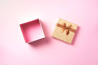 Pembe arka planda parıldayan altın parıltılı hediye kutusu. Romantik kart. Yeni yıl, Noel, Sevgililer Günü tebrikleri. Metni kopyala Üst manzara, düz uzanma.