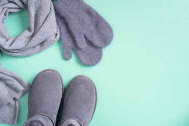 Moda konsepti yatıyordu. Kış sıcacık giysileri mavi arka planda yatıyordu. Yünlü kadın kıyafetleri, atkı, botlar. Üst görünüm, boşluğu kopyala. Pankart