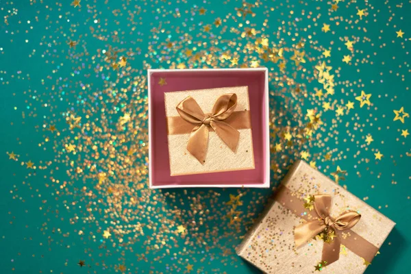 緑の背景に輝く金の輝きを持つギフトボックス。ロマンチックなカードだ。新年、クリスマス、挨拶のバレンタインデーの概念。テキストをコピーします。トップビュー、フラットレイアウト. — ストック写真