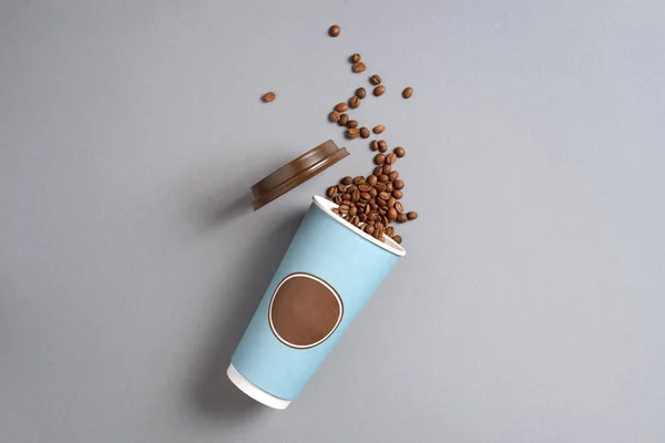 Take away coffee cup and coffee beans on grey background. Top view. Copy space. Minimal composition, layout for design. Coffee concept.