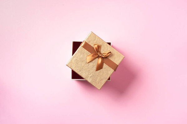 Valentines Day. Golden gift box on pink background. Top view. Copy space. Festive backdrop for holidays: Birthday, Valentines day, Christmas, New Year. Flat lay style. Banner