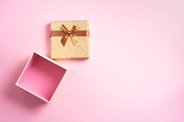 Valentines Day. Golden gift box on pink background. Top view. Copy space. Festive backdrop for holidays: Birthday, Valentines day, Christmas, New Year. Flat lay style. Banner