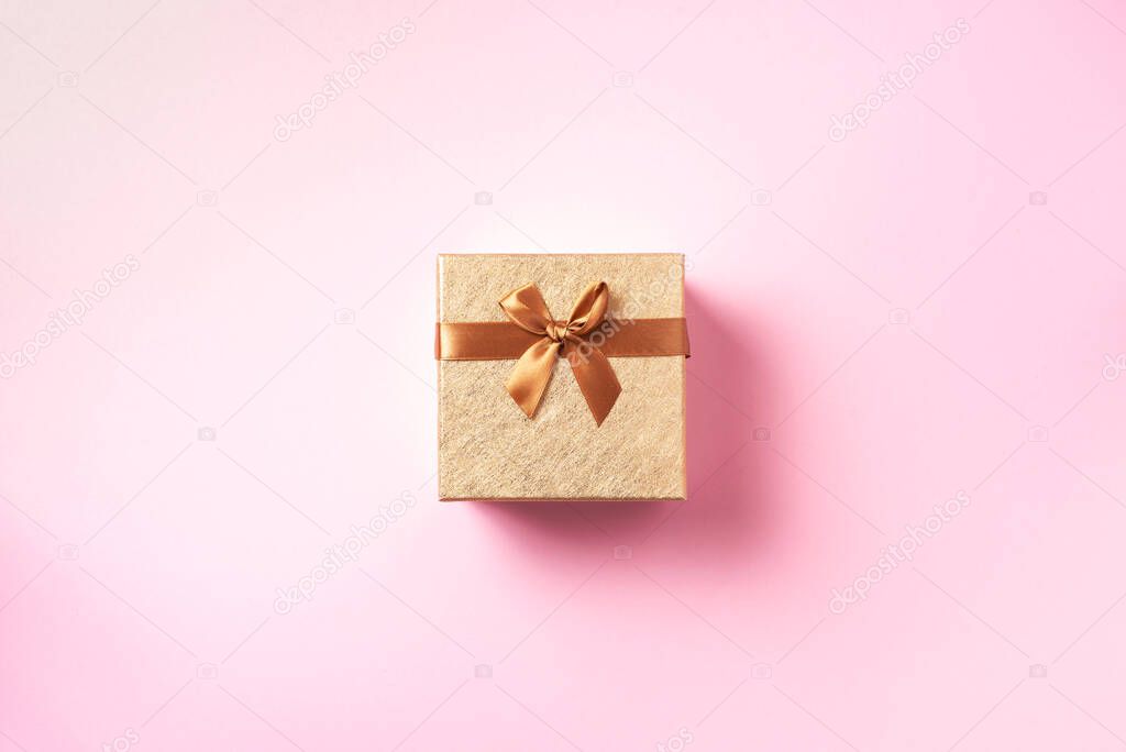 Gift box with sparkling gold glitter on pink background. Romantic card. New year, Christmas, Valentines day concept of greetings. Copy text. Top view, flat lay.