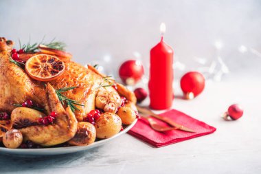 Kızarmış tavuk, şenlikli dekorasyon, mumlar, çimento arka planda hafif çukur. Geleneksel yeni yıl tatili ya da Noel kutlaması yemeği. Arkadaş ya da aile yemeği. Şenlikli Noel masası.